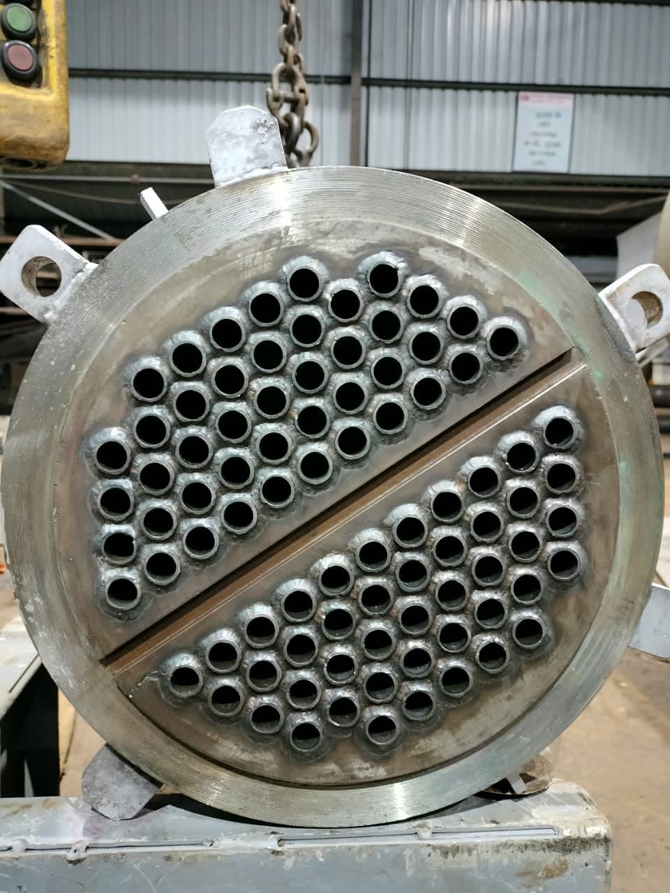 A finished tube sheet: tubes expanded and seal welded, pass partition groove machined across the face.