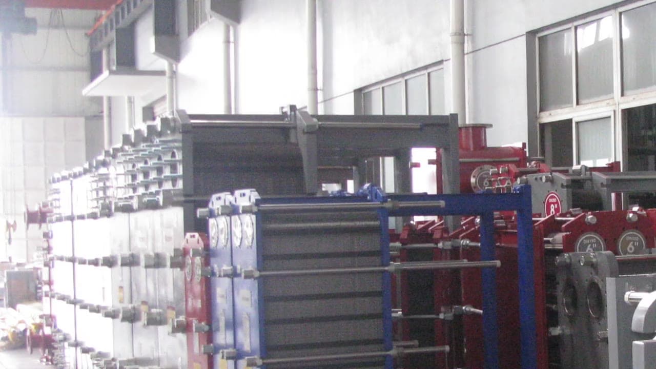 A row of gasketed plate heat exchangers in blue, red and grey frames on the assembly floor