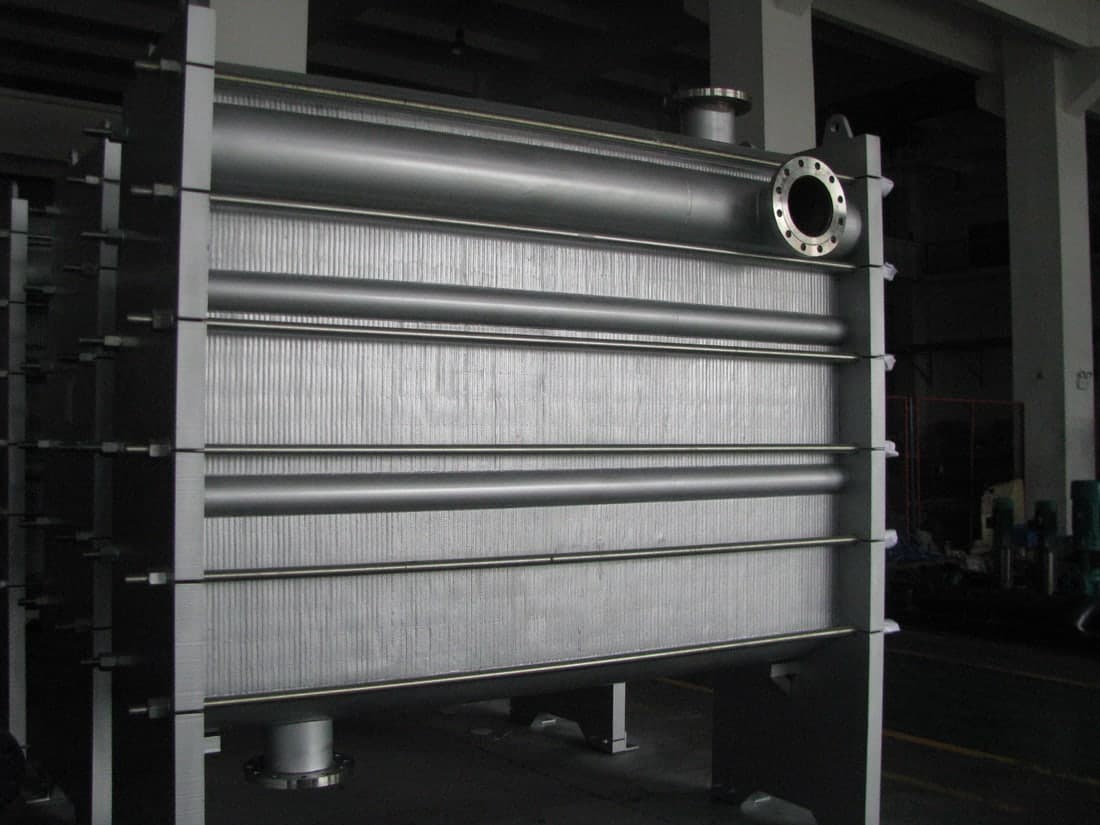 Headers welded the length of the pack, carrying the flow into every channel without a gasket at any joint.