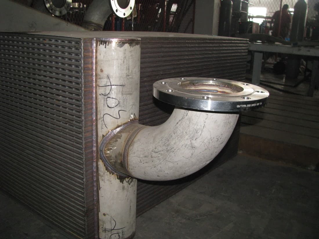 The nozzle welded to the header: the connection a fully welded unit makes in steel where a gasketed one makes it in rubber.