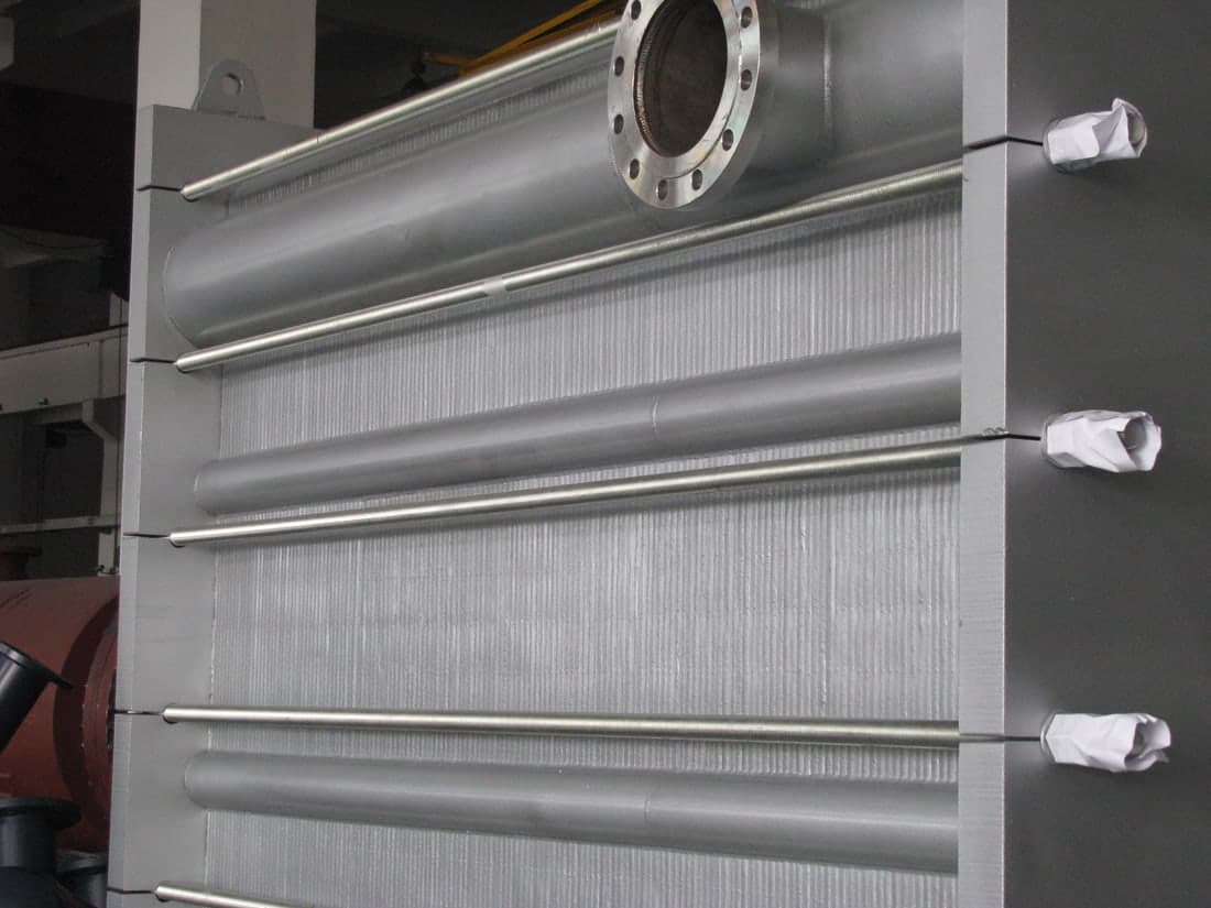 The welded headers seen close, running across the edge of the plate pack.