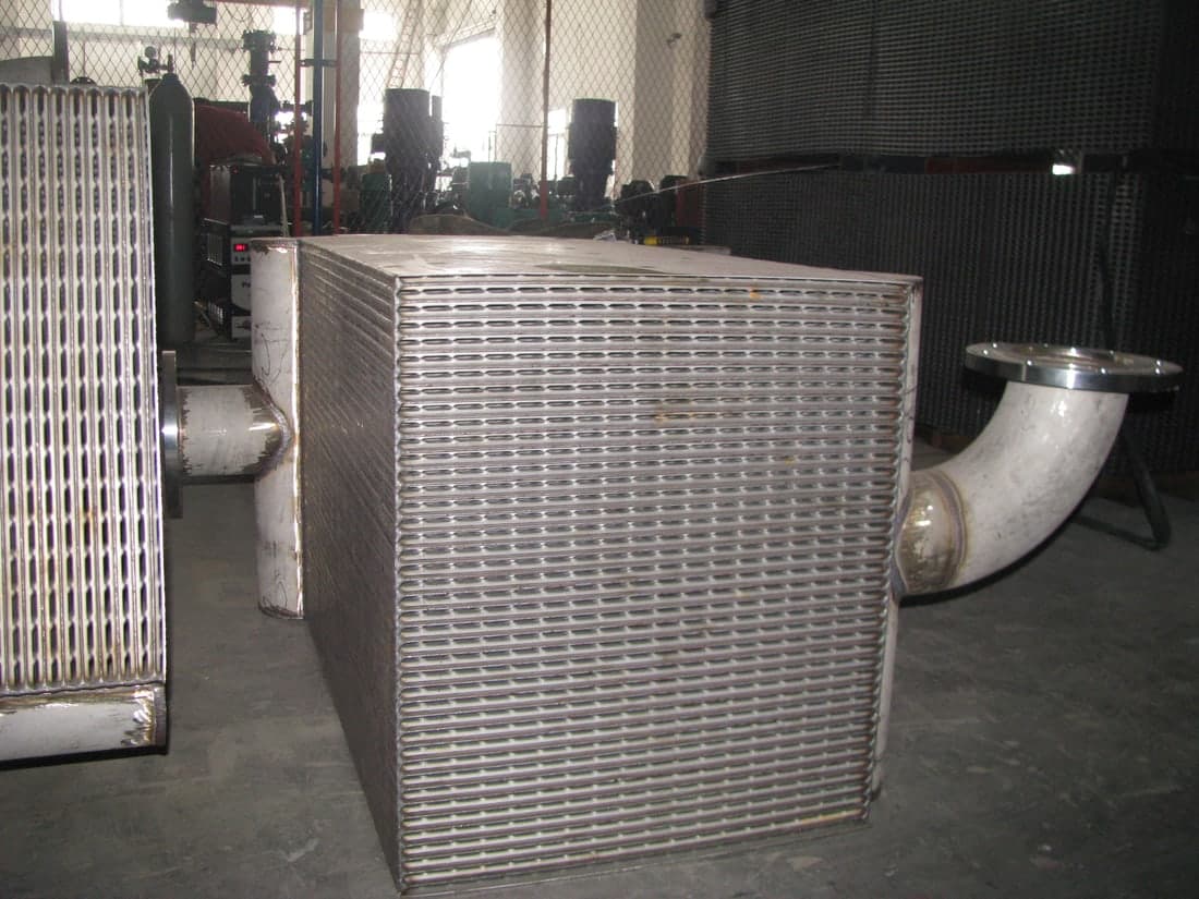 Two packs on the shop floor, elbows welded to the headers and the plate edges exposed along the flank.