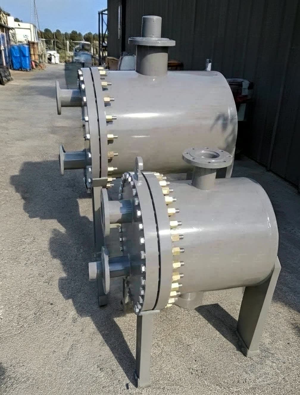 Finished plate & shell units before despatch — the welded plate pack sealed inside a cylindrical pressure shell.