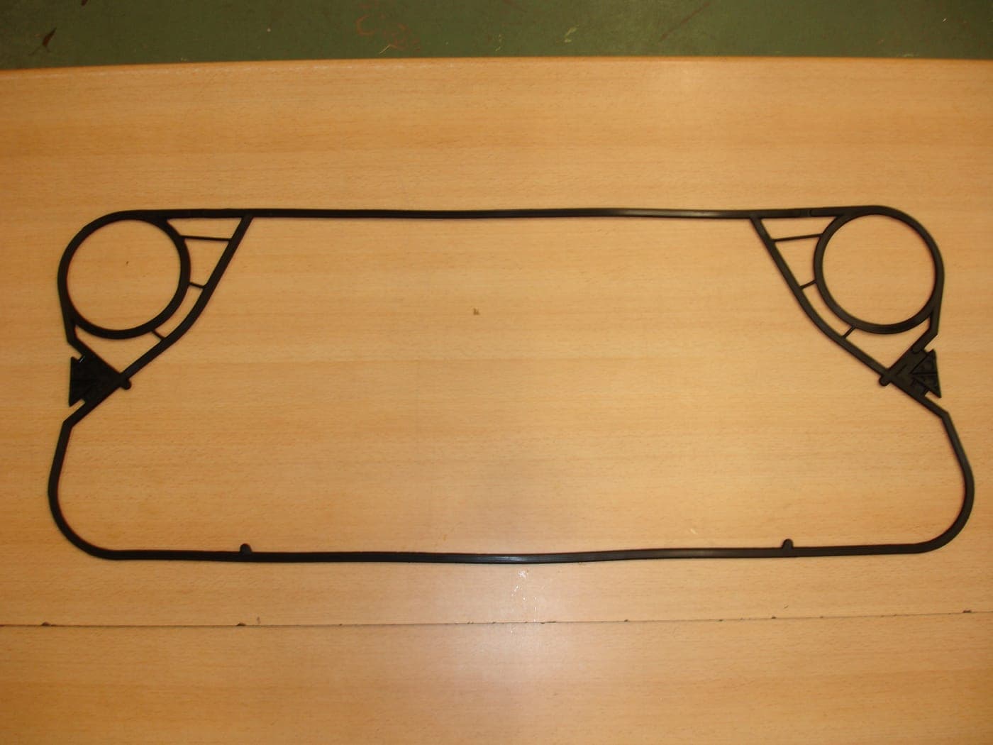 A moulded replacement gasket. The two loops seal one pair of ports out of the channel. For the Tranter GC26, supplied by Synergizing Technologies.